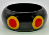 Judith Evans black resin bangle with red and yellow bullseye dots